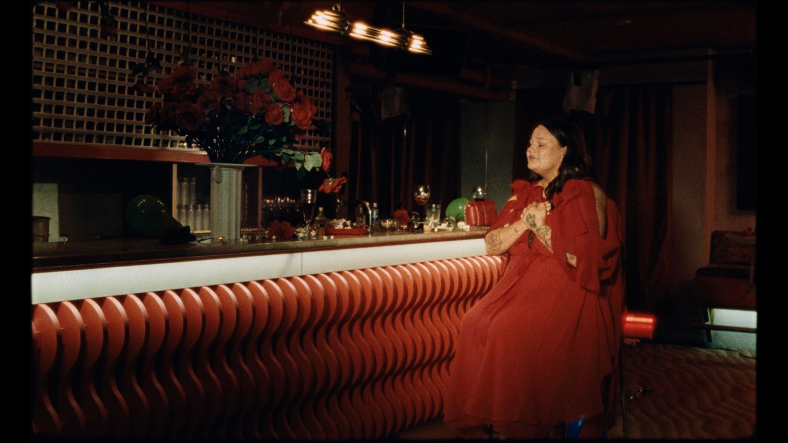 a woman in a red dress standing in front of a bar