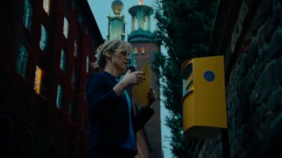 a woman standing next to a yellow mailbox