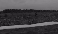 a black and white photo of a man walking in a field