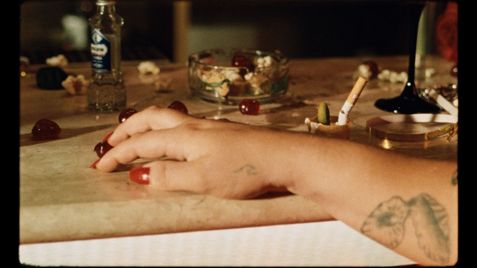 a woman's hand on a table with a bottle of alcohol