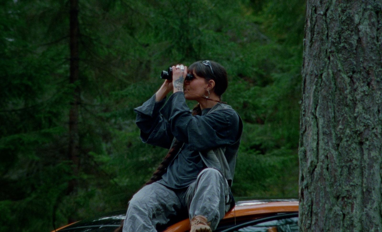 a woman sitting on top of a car next to a tree