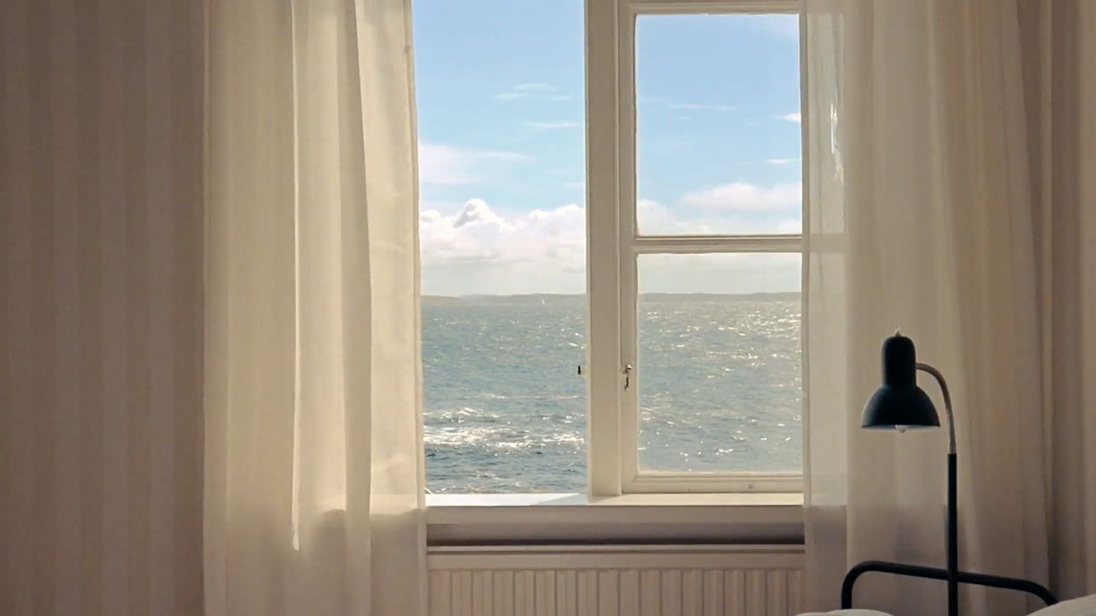 a bedroom with a large window overlooking the ocean