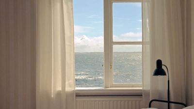 a bedroom with a large window overlooking the ocean