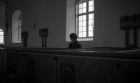 a person sitting in a church looking out the window