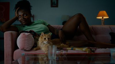 a woman sitting on a couch next to a cat