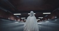 a woman in a white cloak standing in a hallway