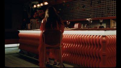 a woman sitting at a bar in a red dress