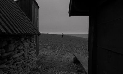 a black and white photo of a person walking on a beach