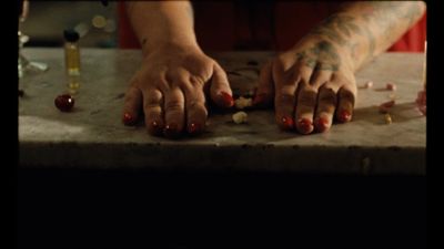 a person's hands on a table with a bottle of wine