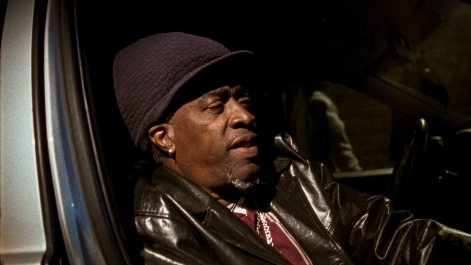 a man in a leather jacket sitting in a car