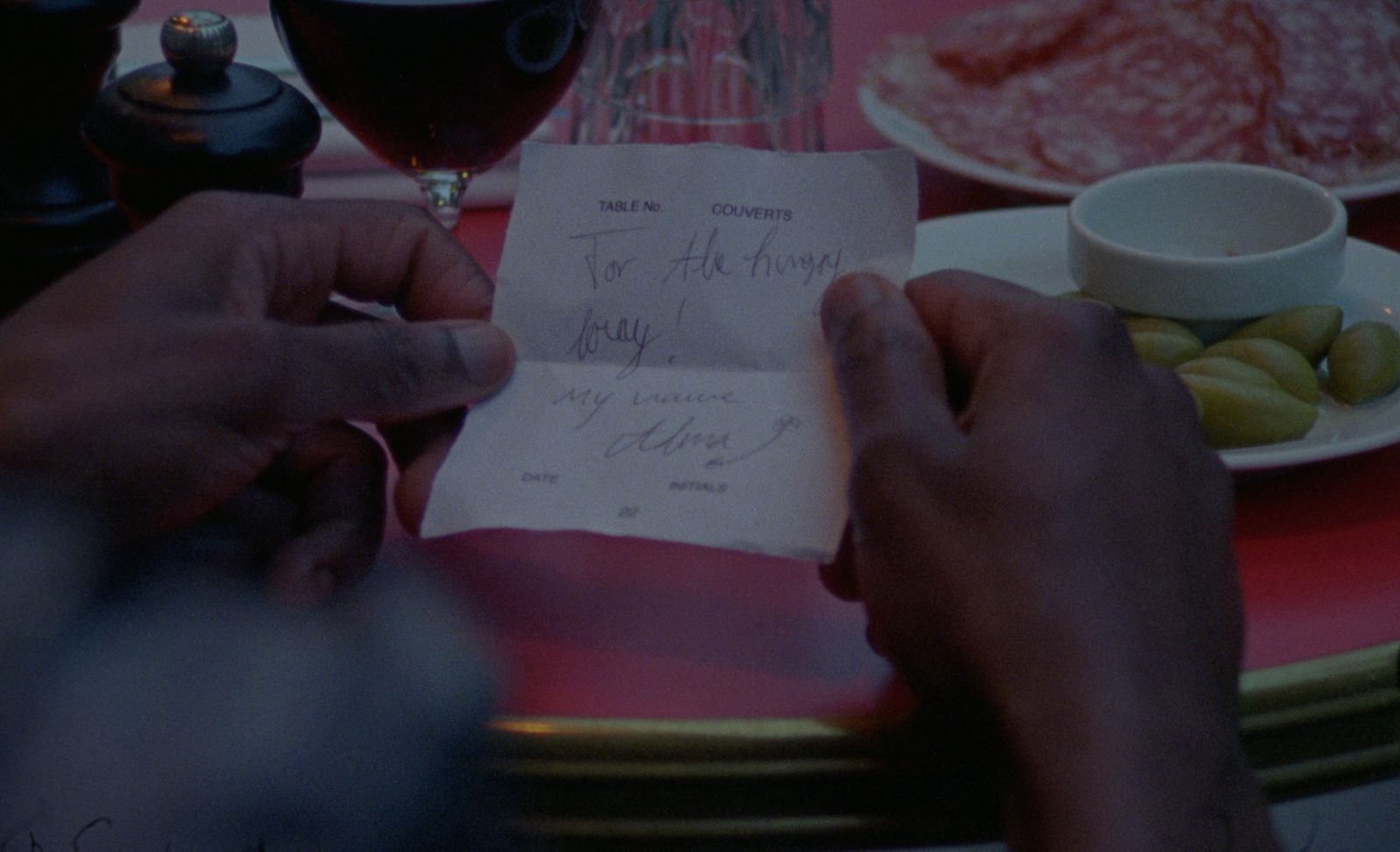 a person holding a piece of paper next to a glass of wine