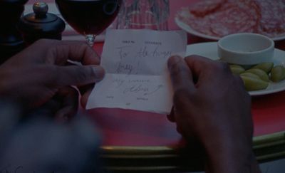 a person holding a piece of paper next to a glass of wine