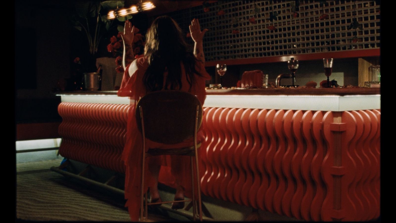 a woman sitting at a bar with her arms in the air