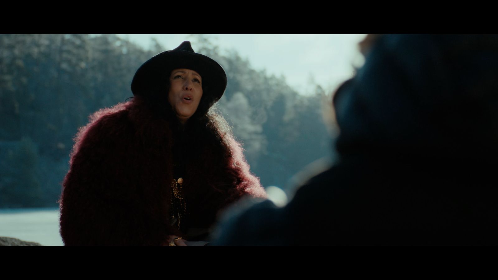 a woman in a fur coat talking to a man