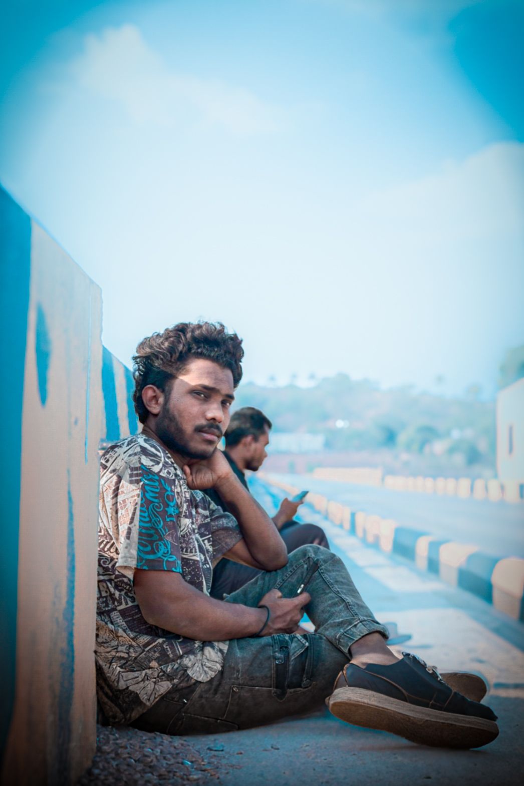 a man sitting on the ground next to a wall