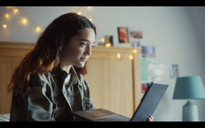 a woman sitting on a bed using a laptop computer