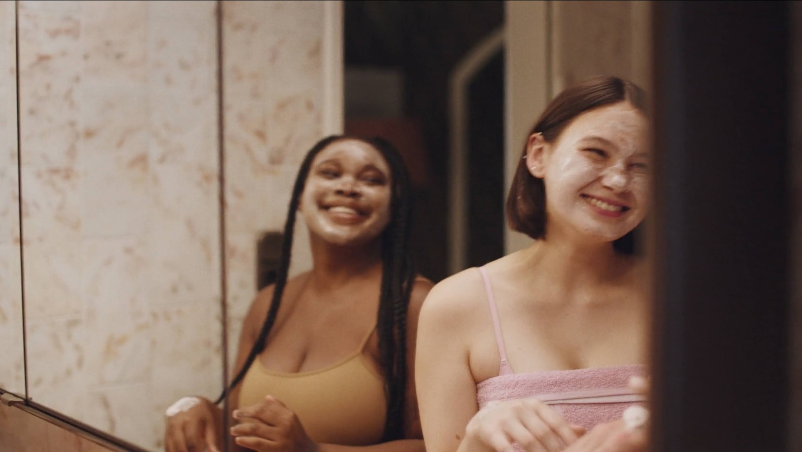 a couple of women standing in front of a mirror