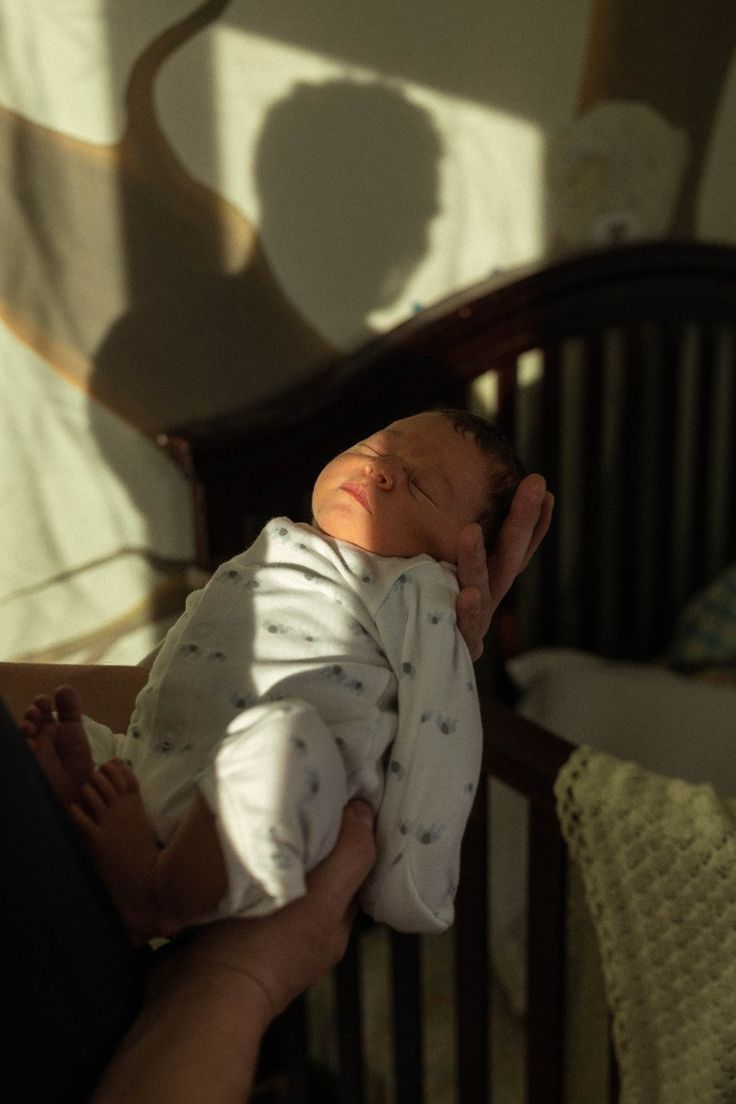 a person holding a baby in a crib