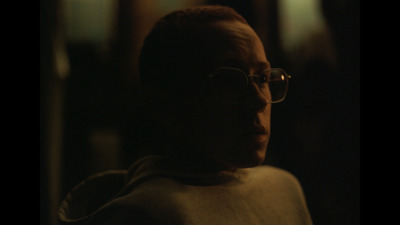  a man wearing glasses in a dark room