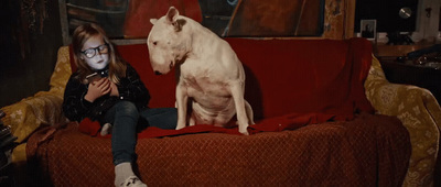 a girl sitting on a couch next to a dog