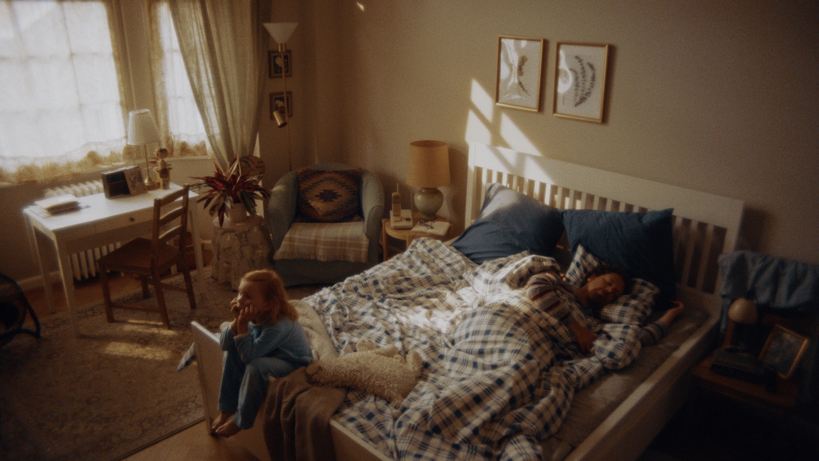 a little girl sitting on a bed with a teddy bear