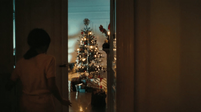 a woman standing in front of a christmas tree