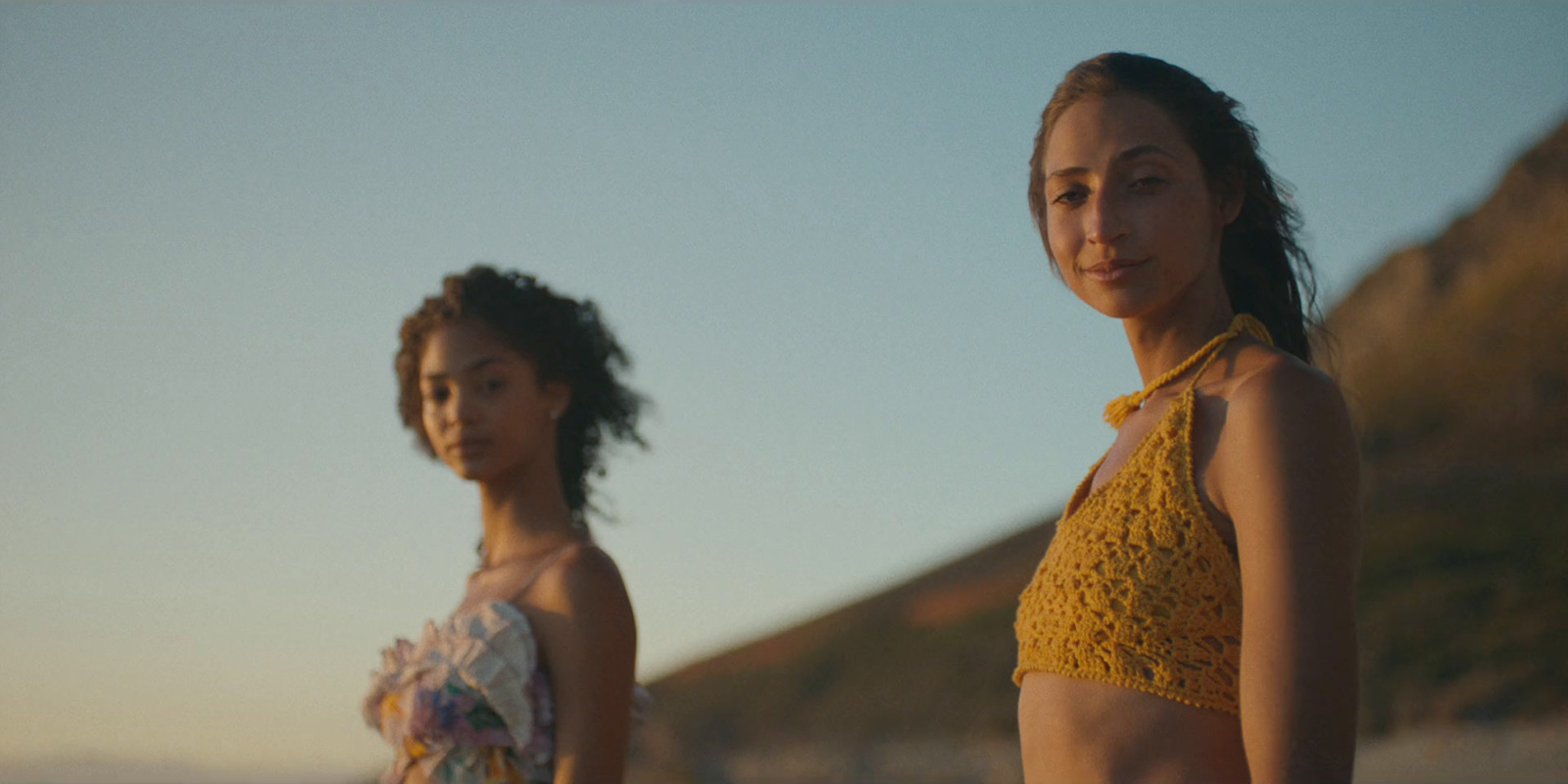 two women standing next to each other on a beach