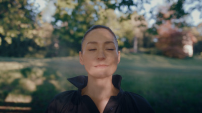 a woman with her eyes closed in a park