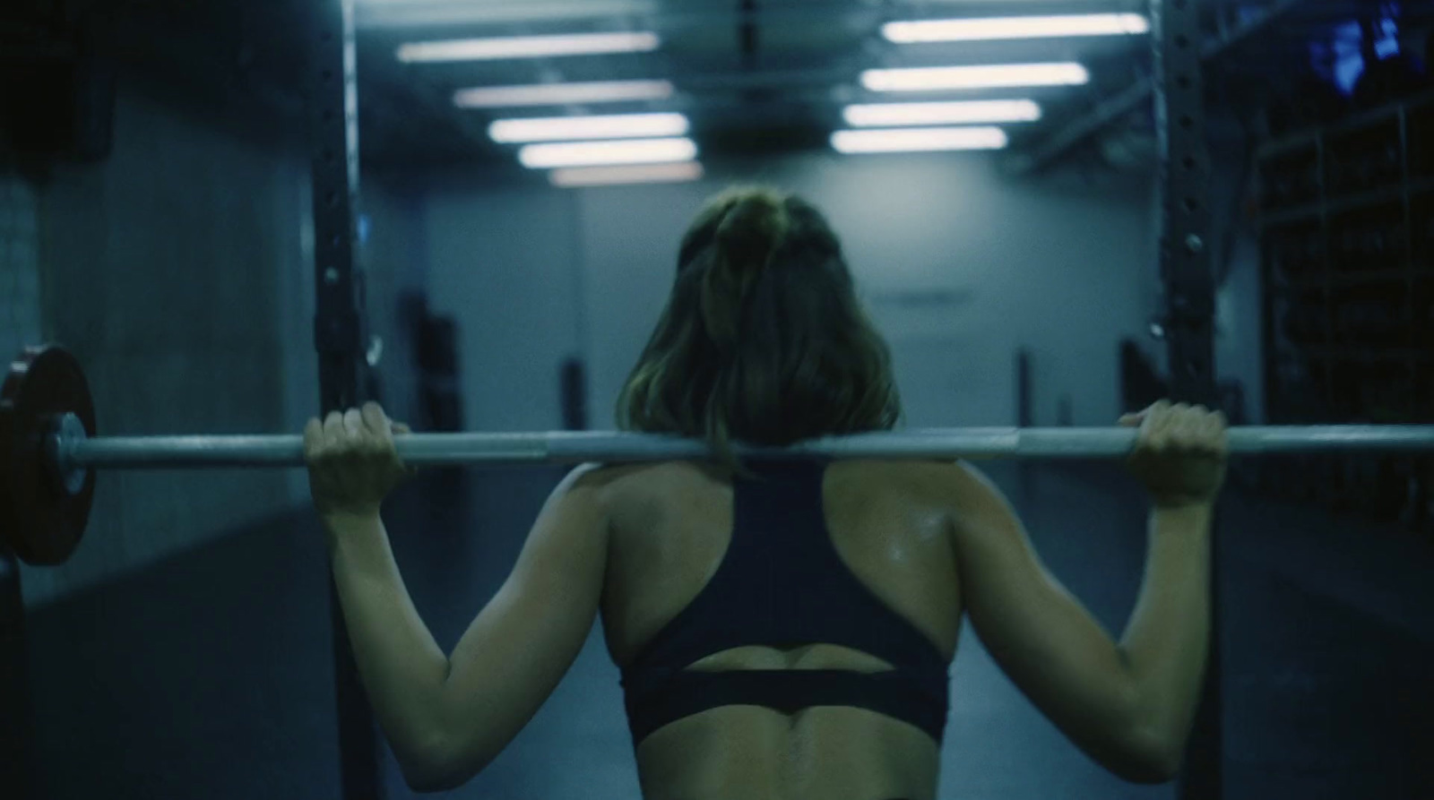 a woman holding a bar in a gym