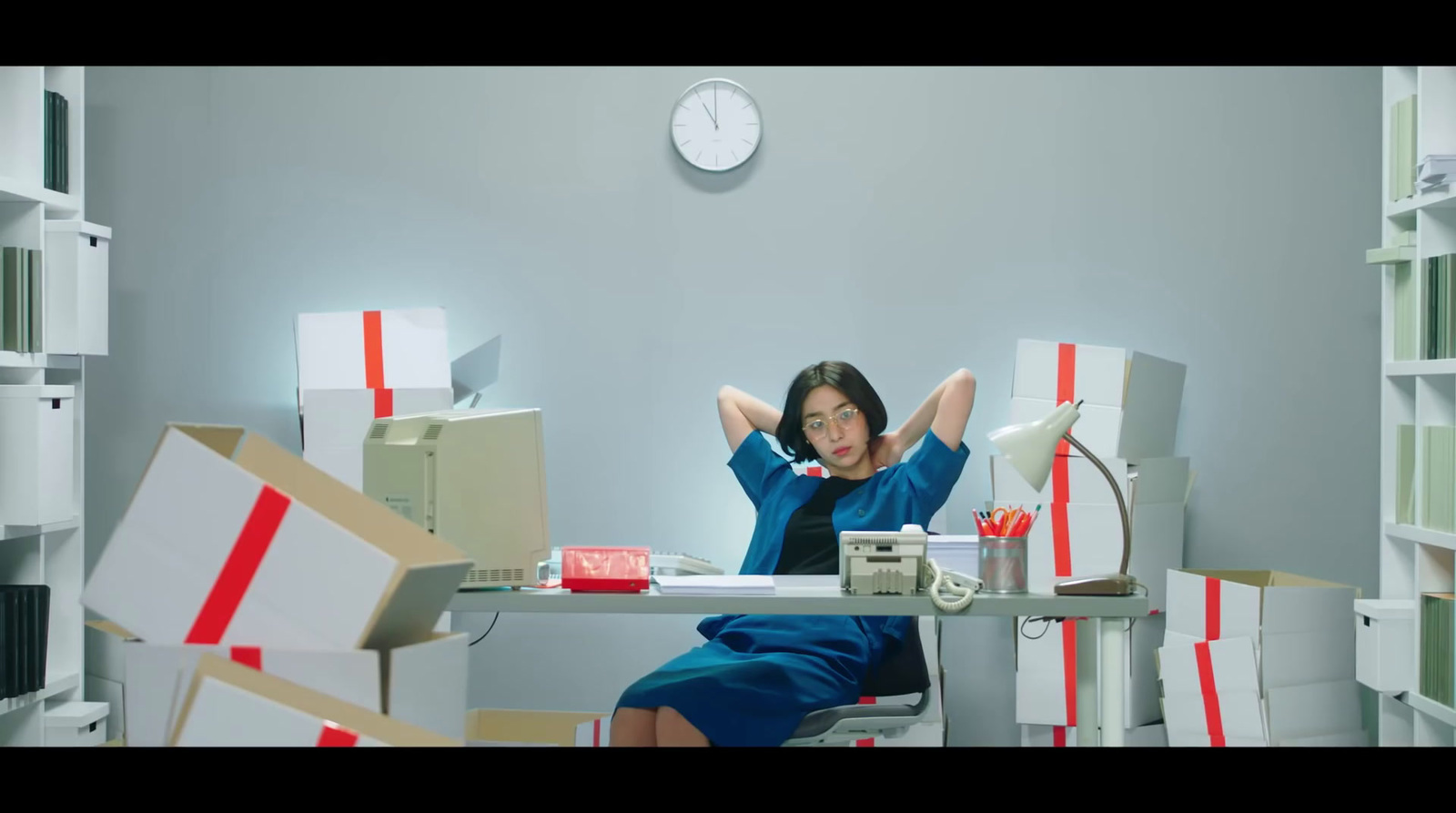 a woman sitting at a desk surrounded by boxes