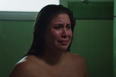 a shirtless woman in a green bathroom