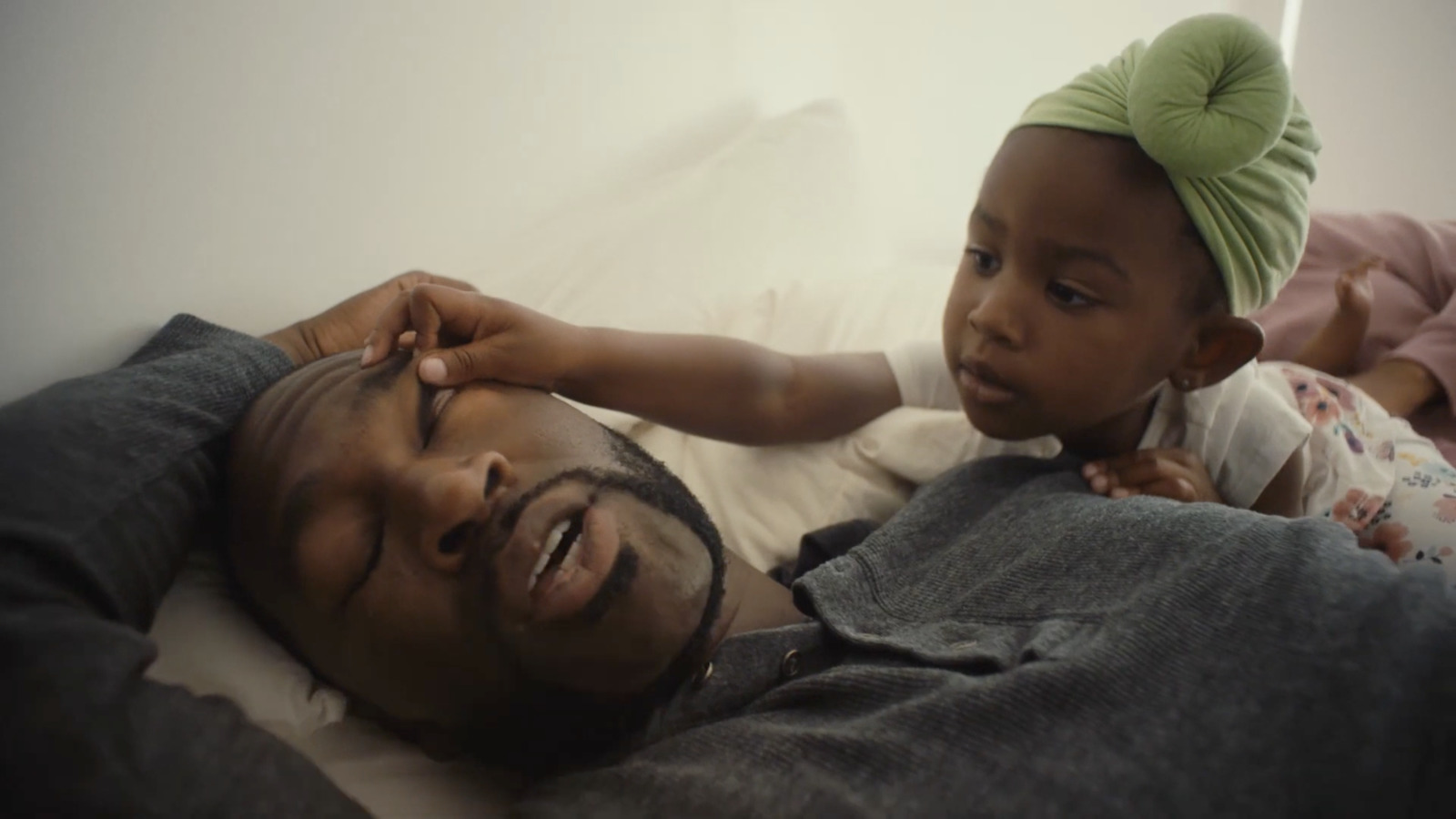 a man laying on top of a bed next to a child