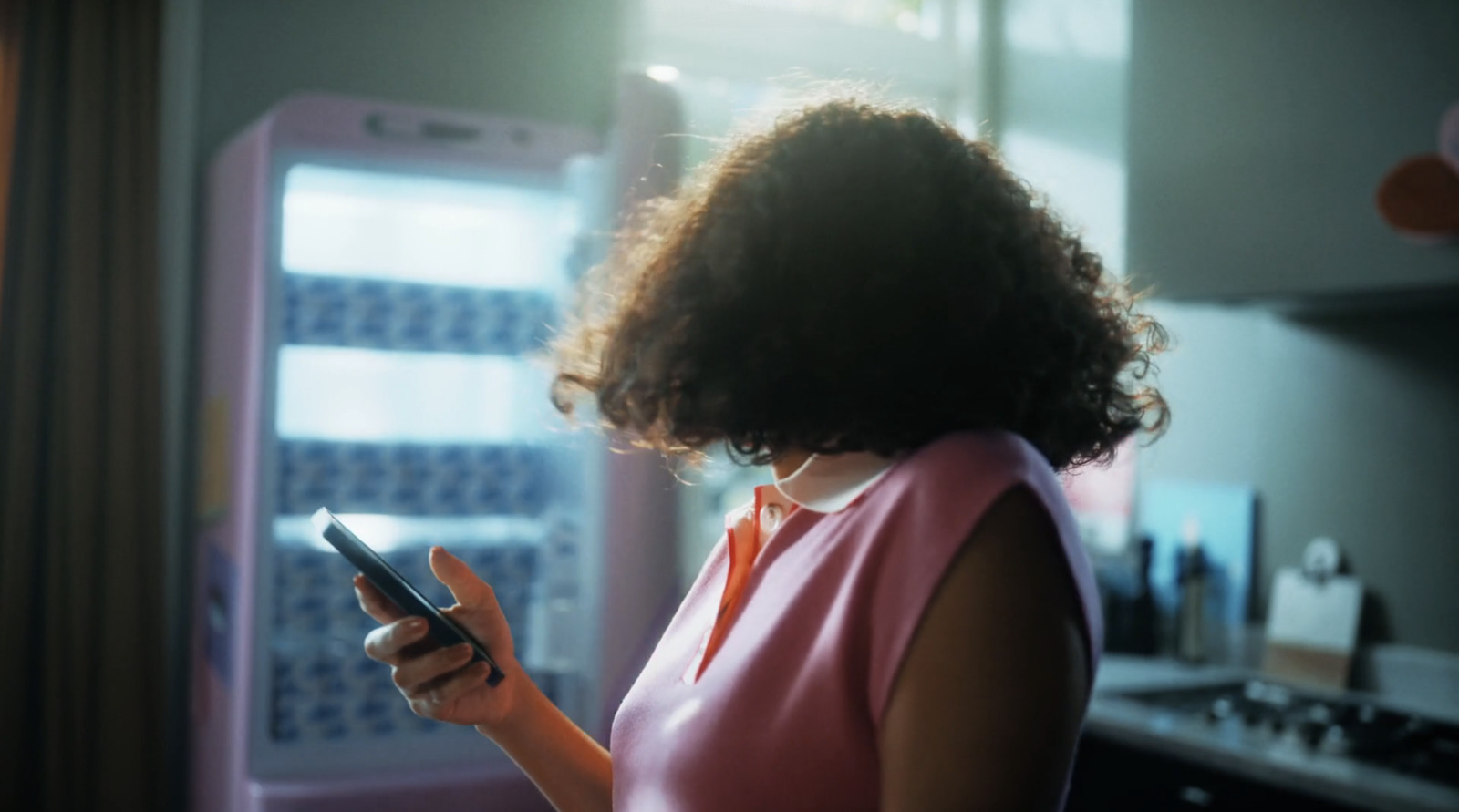 a woman looking at her phone in front of a refrigerator