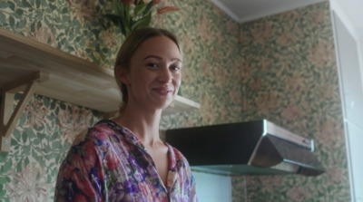 a woman in a floral shirt standing in front of a kitchen