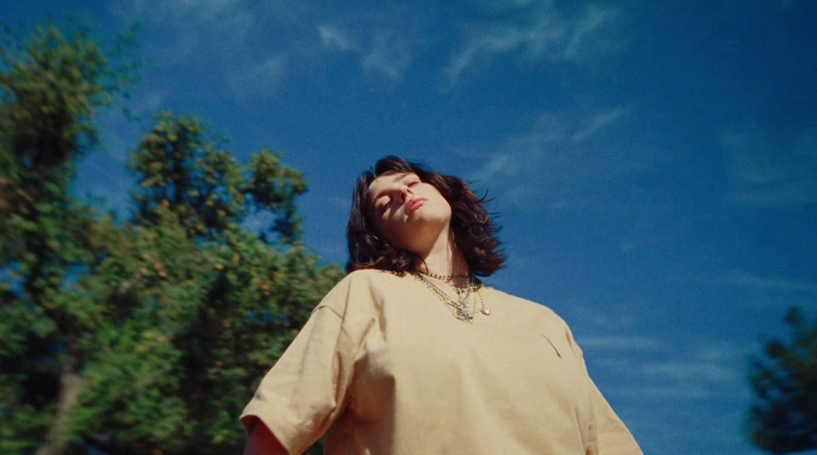 a woman standing in front of a tree with her eyes closed