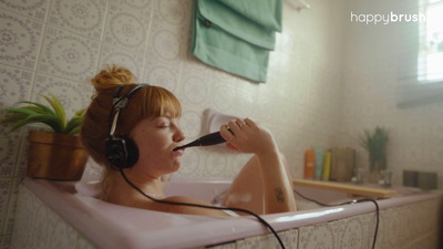 a woman in a pink bath tub with headphones on