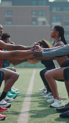 a group of people standing on top of a field holding hands