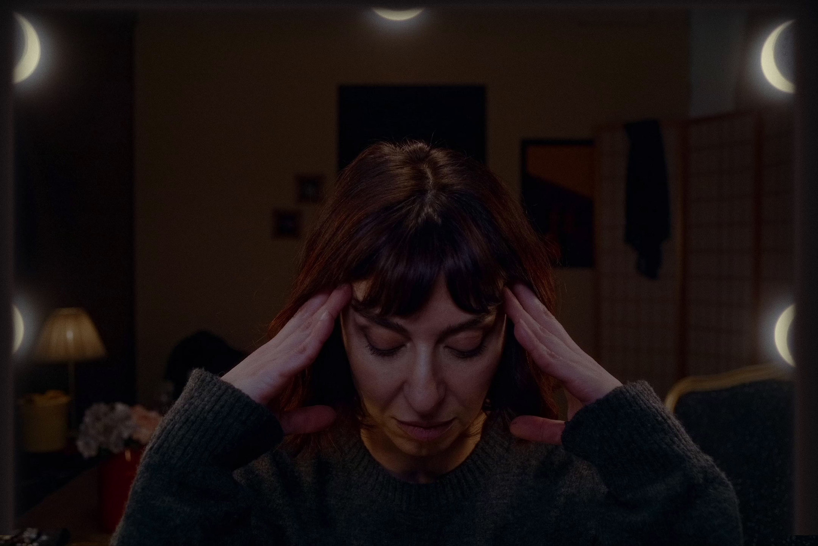 a woman holding her head in front of a mirror