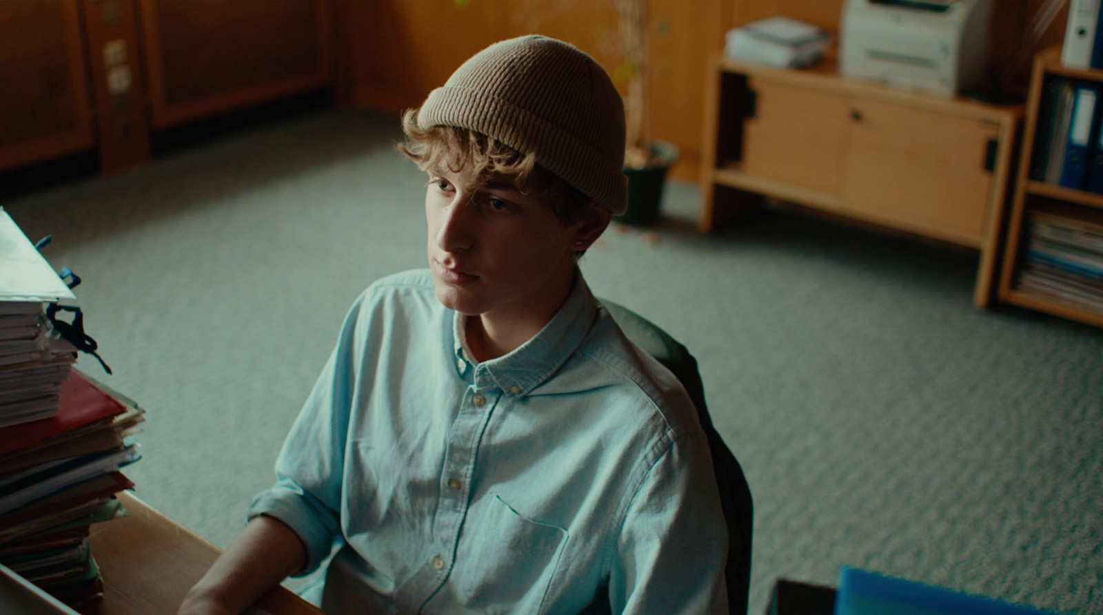 a boy sitting at a desk with a pile of papers