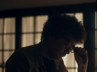  a man with curly hair and glasses looking at a cell phone