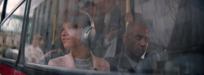 a woman is sitting on a bus with headphones on