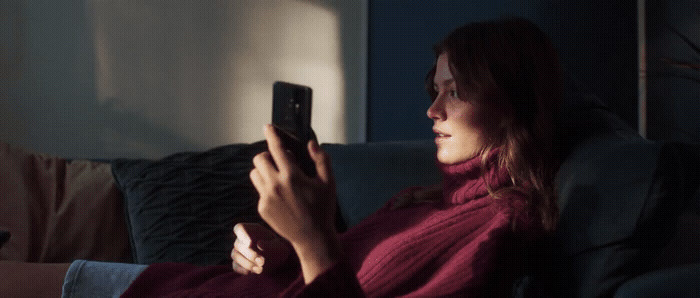 a woman sitting on a couch holding a cell phone