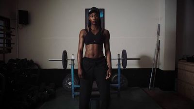 a woman standing in front of a barbell in a gym