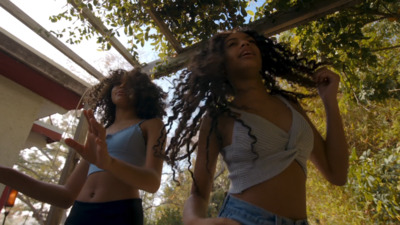 two women standing next to each other in front of trees