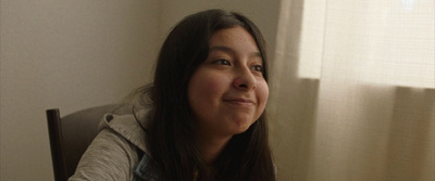 a woman sitting in front of a window next to a curtain