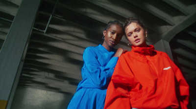 two women standing next to each other in front of a building