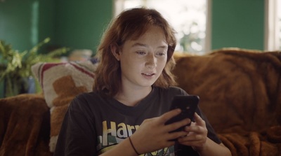 a woman sitting on a couch looking at a cell phone