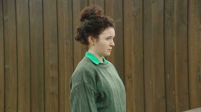 a woman standing in front of a wooden fence