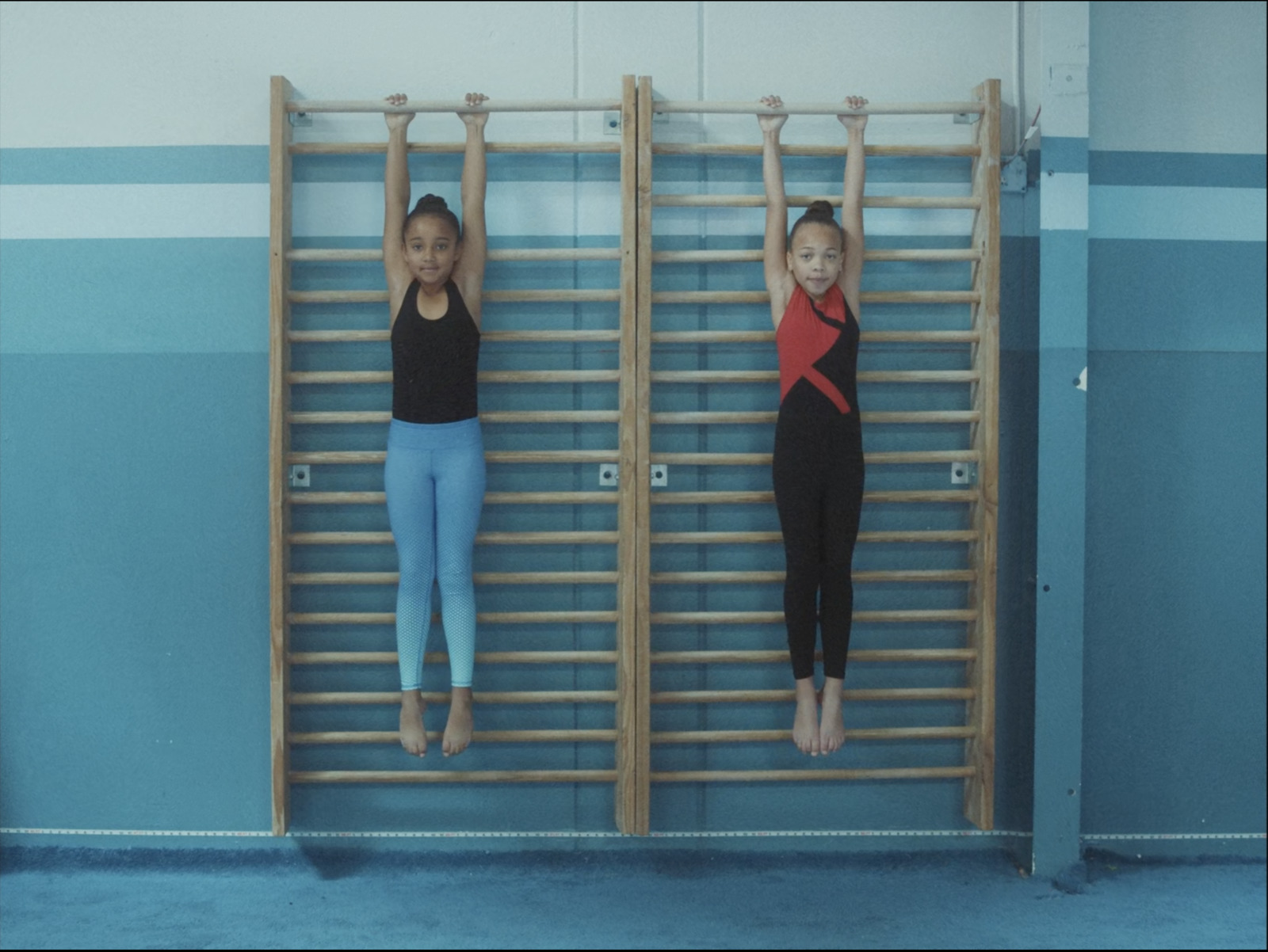 two young girls hanging on a wall with their hands in the air