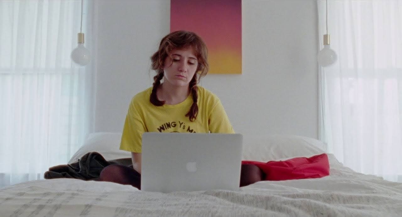 a woman sitting on a bed using a laptop computer